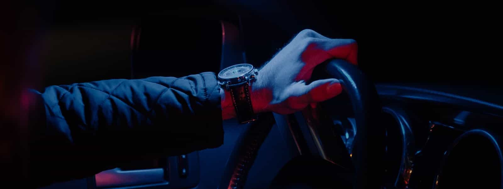 Mano de un conductor profesional sobre el volante, de noche