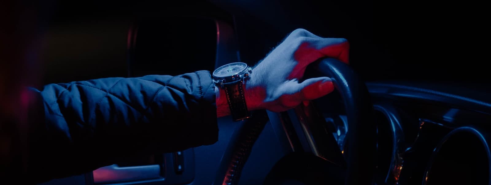 Mano de un conductor profesional sobre el volante, de noche